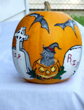 Rest in Peace cat poping out the top of a pumpkin in a graveyard